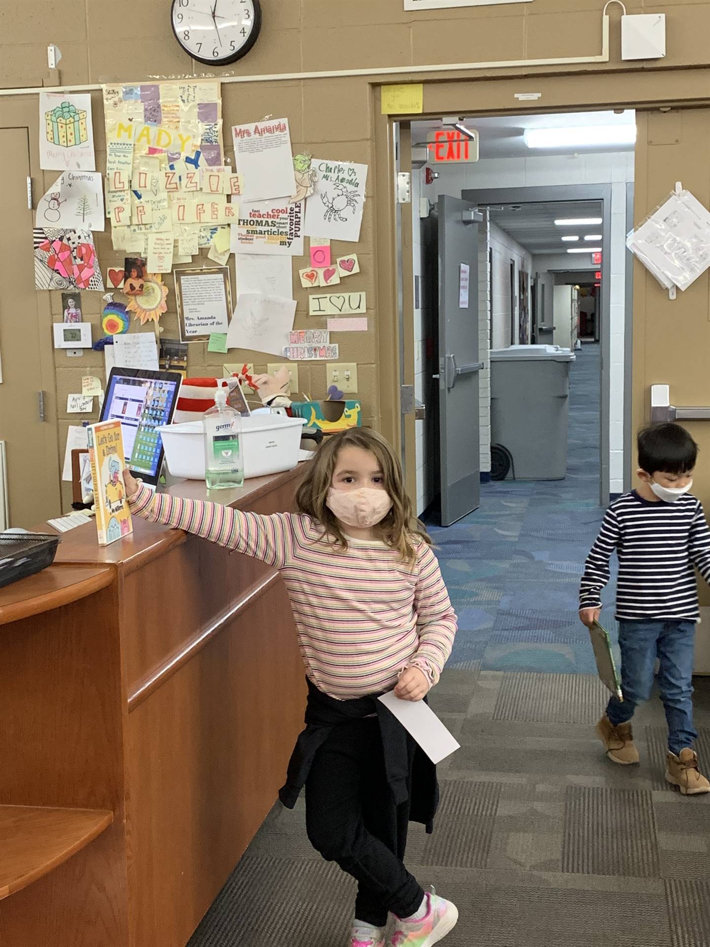 Kindergartener standing at desk in library