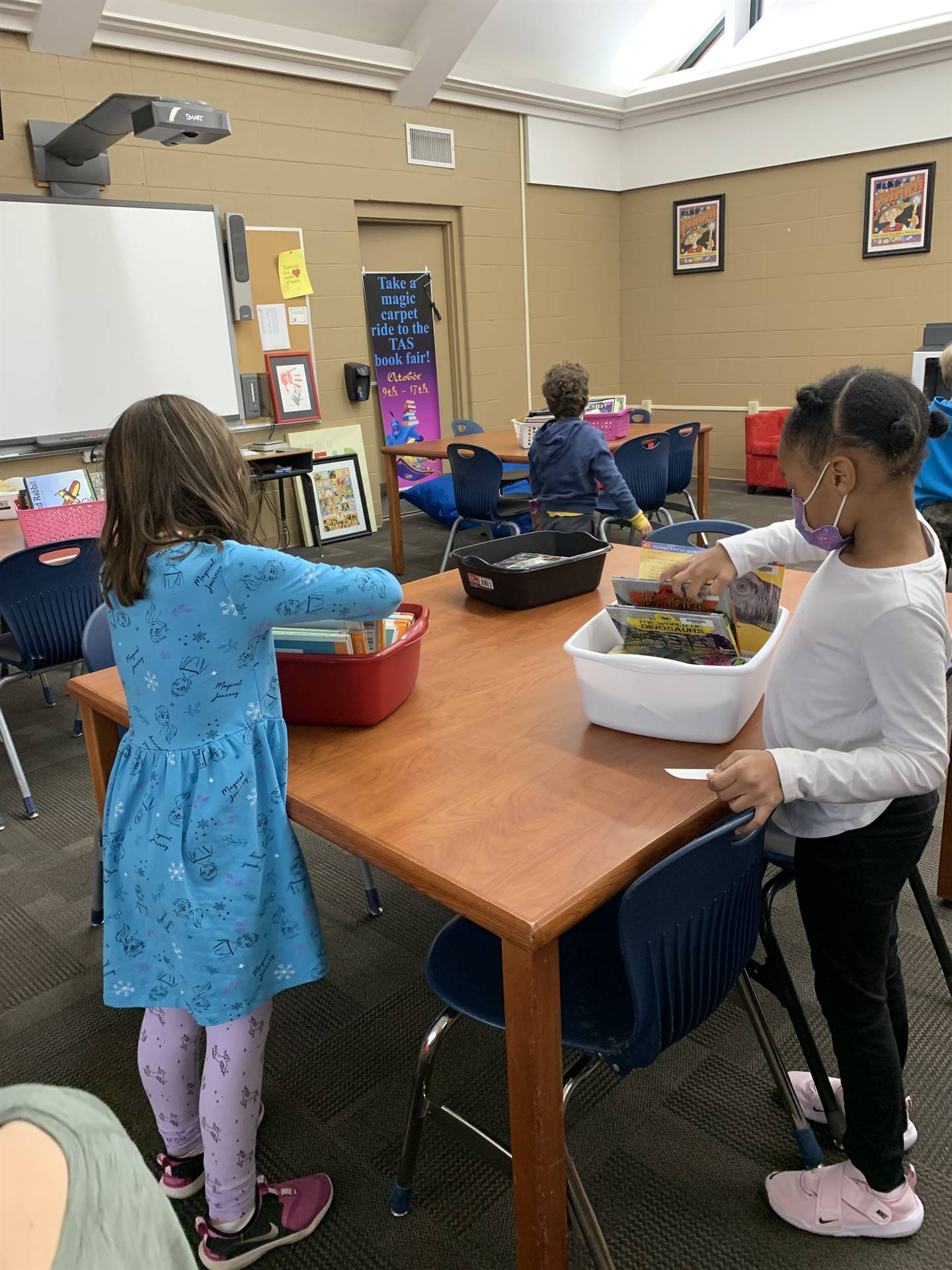 kindergarten students standing at a desk in the library with their books